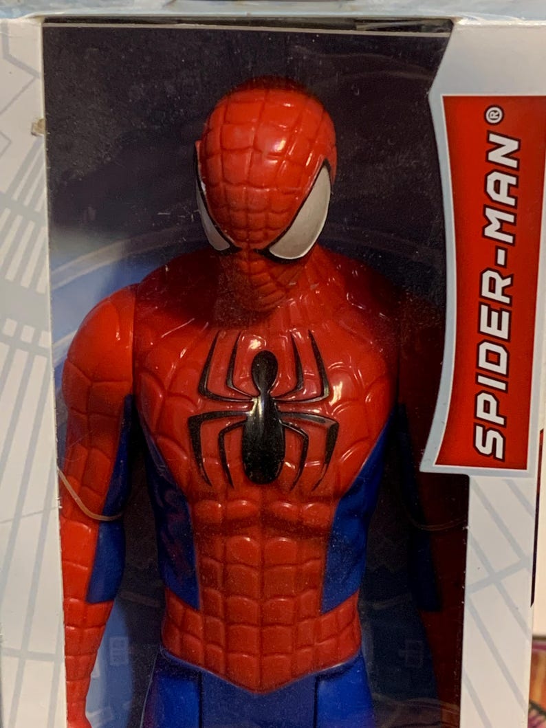 May include: A red and blue Spider-Man action figure with a black spider logo on the chest. The figure is packaged in a white box with the words "SPIDER-MAN" in red.