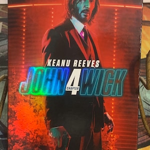 Puede incluir: Pack combinado de Blu-ray, DVD y digital de John Wick: Capítulo 4. La portada presenta a Keanu Reeves con un traje sobre un fondo rojo y naranja. El título "John Wick" está en letras grandes e iridiscentes.