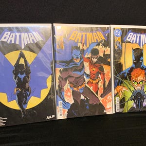 May include: Three Batman comic books with vibrant covers. The first features Batman in a dynamic pose against a yellow backdrop. The second shows Batman and Robin. The third comic book cover displays Batman and the Riddler. All comics have the word "Batman" in bold letters.