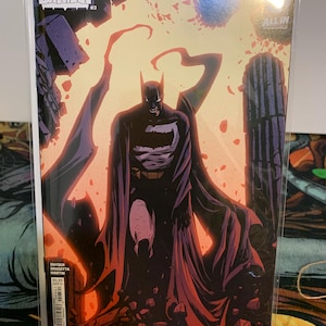May include: A comic book cover for "Absolute Batman #3" featuring Batman in a dark purple and black costume against a fiery orange and red background. The cover includes the text "ALL IN" and the names Snyder, Dragotta, and Martin.