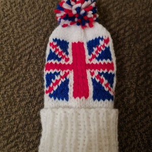 May include: White knitted hat with a red, white and blue pom-pom on top. The hat features a knitted Union Jack design.