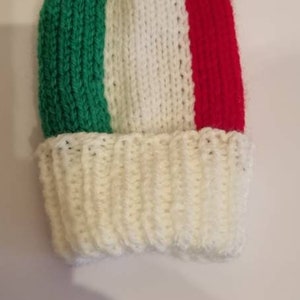 May include: A knitted hat with a pom-pom on top. The hat is green, white and red, resembling the Italian flag.