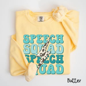 May include: A yellow sweatshirt with the text "SPEECH SQUAD" in blue and green letters with a lightning bolt graphic. The sweatshirt is made of a soft, comfortable material and is perfect for everyday wear.