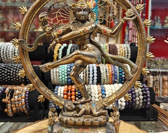 May include: A bronze statue of the Hindu deity Shiva Nataraja, the Lord of Dance, in a dynamic pose within a circular frame. The statue features intricate details, including multiple arms, jewelry, and a snake. The base depicts a figure lying down.