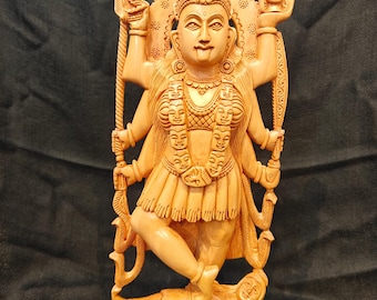 Può includere: Una scultura in legno dettagliata di una divinità con più braccia, in piedi su una figura. La scultura è scolpita in legno di colore chiaro, con dettagli intricati nei vestiti, nei gioielli e nelle espressioni facciali. La divinità tiene in mano vari oggetti.