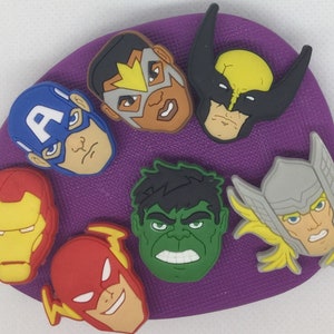 Op de afbeelding: Set van tien kleurrijke superhelden-schoencharms. De charms tonen personages zoals Captain America, Iron Man, Hulk, Thor en Wolverine. De charms zijn gemaakt van duurzaam plastic en perfect om een ​​persoonlijke touch aan je schoenen toe te voegen.