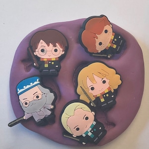 May include: Five colorful Harry Potter character figurines with wands. The characters are Harry Potter, Ron Weasley, Hermione Granger, Draco Malfoy, and Albus Dumbledore. The figurines are made of silicone and are approximately 2 inches tall.
