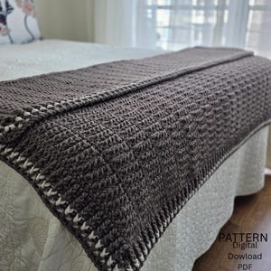 May include: A dark brown crocheted blanket with a textured stitch pattern and a cream-colored border detail. The blanket is draped over a bed. The image includes the text "PATTERN Digital Download PDF" in the bottom right corner.