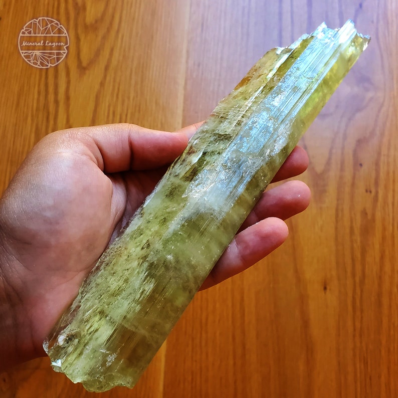 May include: A large, light green, translucent crystal with striations. The crystal is about 10 inches long and has a slightly irregular shape.