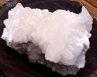 Op de afbeelding: Een grote cluster van witte selenietkristallen met een licht roze tint. De kristallen zijn in een willekeurig patroon gerangschikt en hebben een glad, glazig oppervlak.
