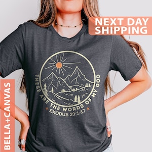 May include: Heather dark gray t-shirt with a graphic of mountains, a sun, and the text "These are the words of my God Exodus 20:1-17".