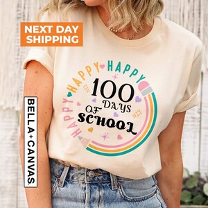 May include: A white t-shirt with a rainbow design and the text "Happy 100 Days of School" in black lettering.