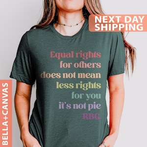 May include: A dark green t-shirt with the text "Equal rights for others does not mean less rights for you it's not pie RBG" printed in rainbow colors.