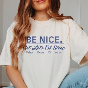 May include: A white t-shirt with a blue graphic that says "BE NICE. Get Lots Of Sleep. Drink Plenty Of Water."