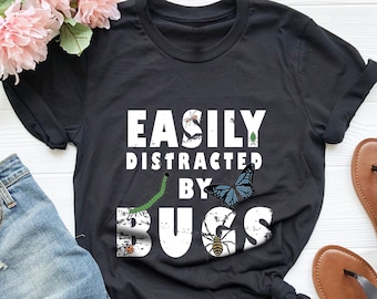 May include: Black t-shirt with white text that reads "Easily Distracted by Bugs". The text is distressed and surrounded by images of bugs, including a butterfly, spider, ladybug, and caterpillar.
