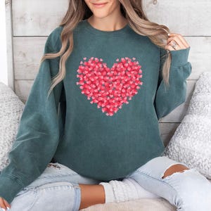 May include: A teal green sweatshirt with a large red heart made of smaller hearts printed on the front.