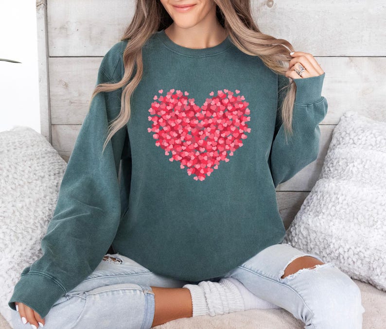 May include: A teal green sweatshirt with a large red heart made of smaller hearts printed on the front.