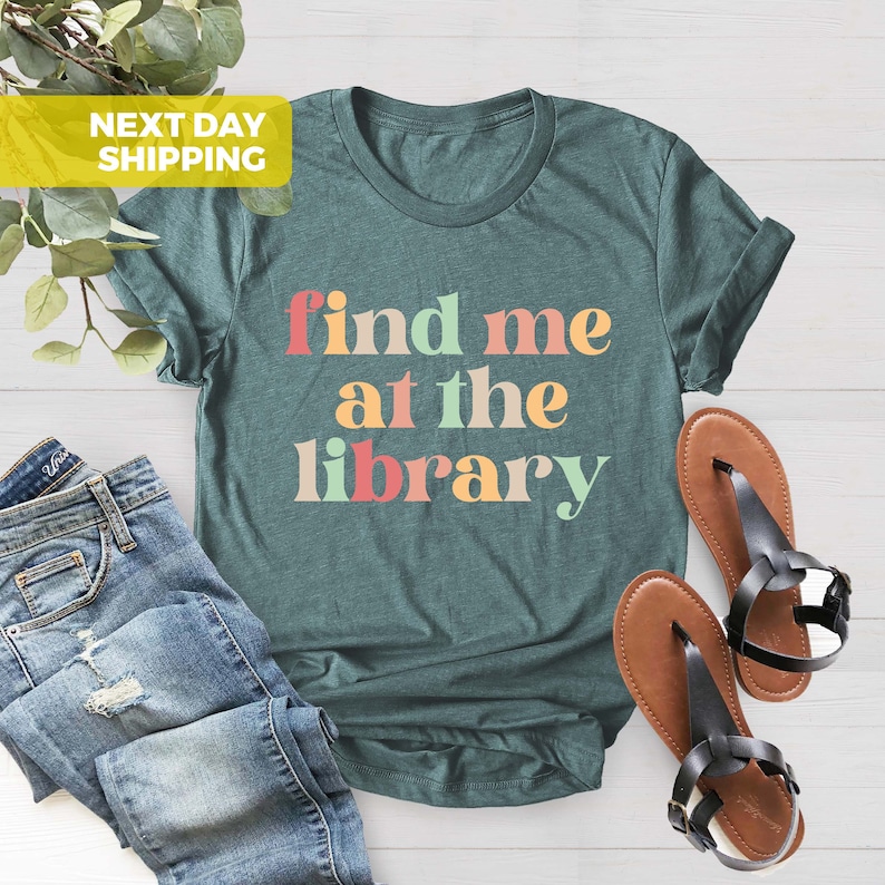 Puede incluir: Camiseta azul turquesa con el texto "find me at the library" en colores arco&iacute;ris.