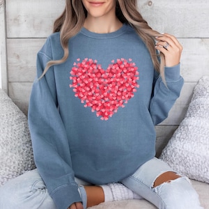 May include: A blue sweatshirt with a large heart design made up of smaller pink hearts.