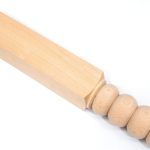 May include: A wooden table leg with a square top and a rounded bottom with a series of decorative beads.