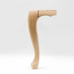 May include: A wooden chair leg with a curved design. The leg is unfinished and has a natural wood color.