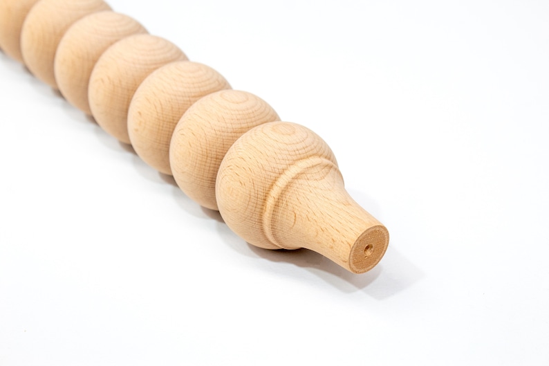 May include: A close-up of a wooden furniture leg with a rounded, beaded design. The leg is unfinished and has a natural wood color.