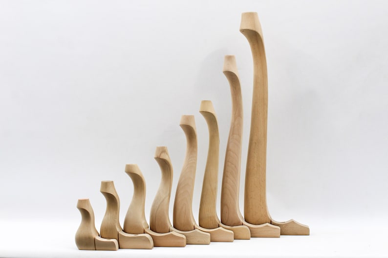 May include: A set of nine wooden chair legs in various sizes, all with a curved design. The legs are made of light-colored wood and are arranged in a row from smallest to largest.
