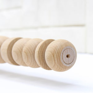 K&ouml;nnte beinhalten: Nahaufnahme einer Holzleiste mit einer Reihe runder Kn&ouml;pfe. Die Holzleiste ist unbehandelt und hat eine nat&uuml;rliche Holzfarbe.