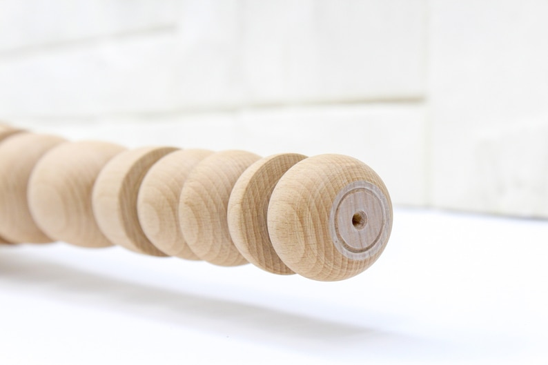 K&ouml;nnte beinhalten: Nahaufnahme einer Holzleiste mit einer Reihe runder Kn&ouml;pfe. Die Holzleiste ist unbehandelt und hat eine nat&uuml;rliche Holzfarbe.