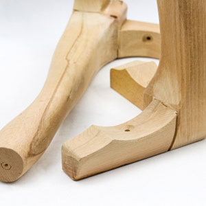 May include: Two unfinished wooden chair legs, one straight and one curved, are shown on a white surface. The legs are made of light-colored wood and have a smooth finish.