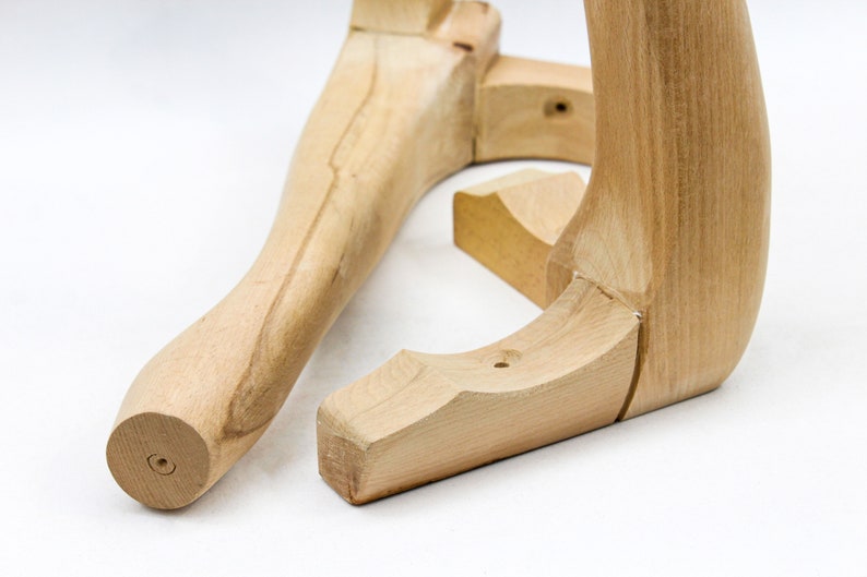 May include: Two unfinished wooden chair legs, one straight and one curved, are shown on a white surface. The legs are made of light-colored wood and have a smooth finish.