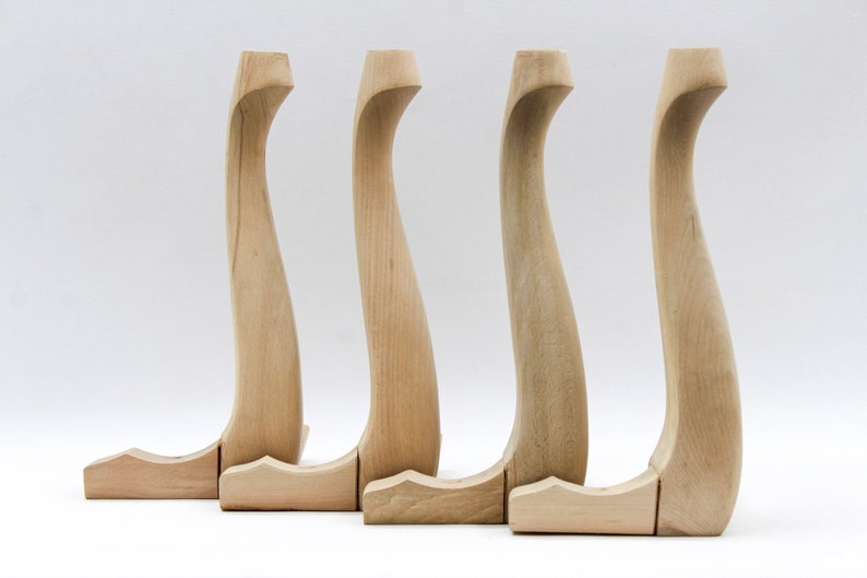 May include: Four unfinished wooden chair legs with a curved design. The legs are arranged in a row from left to right.