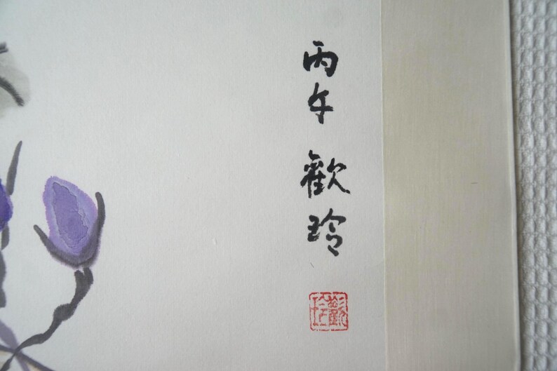May include: A painting on off-white paper featuring purple flower buds with dark gray stems. The artwork includes vertical black Chinese calligraphy characters and a small square red seal stamp at the bottom right corner of the composition.