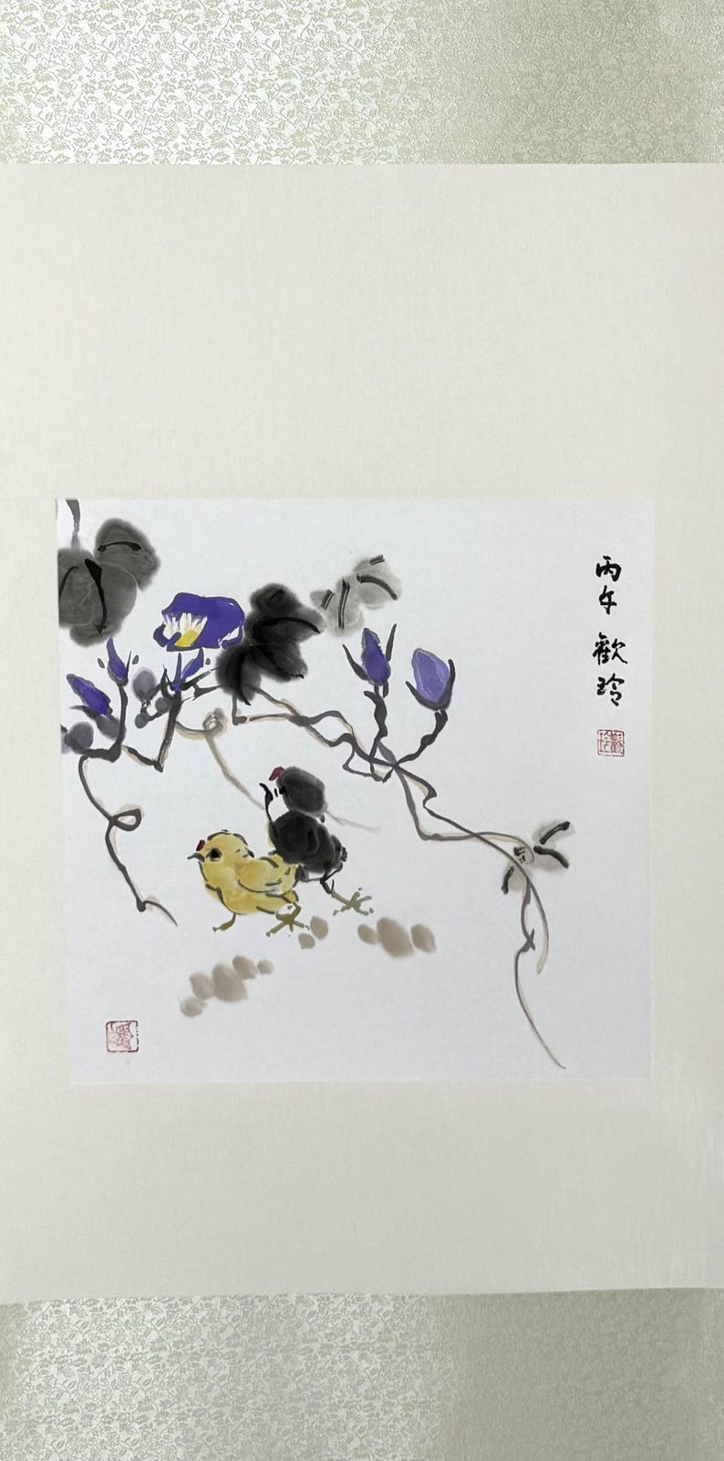 May include: A traditional ink wash painting on white paper featuring two small chicks, one yellow and one black, positioned beneath a flowering vine with purple blossoms and dark grey leaves. Black Chinese calligraphy and red stamps are visible.
