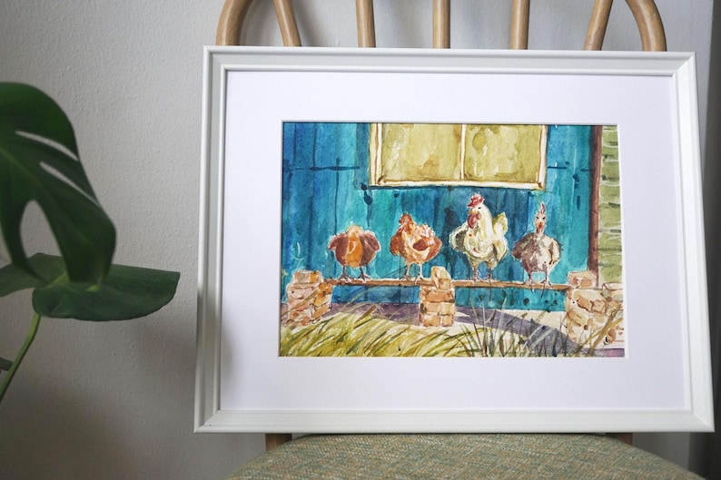 May include: Watercolour painting in a white frame. The artwork depicts four chickens perched on a wooden rail in front of a blue building with a yellow window. The painting has a rustic, country theme.