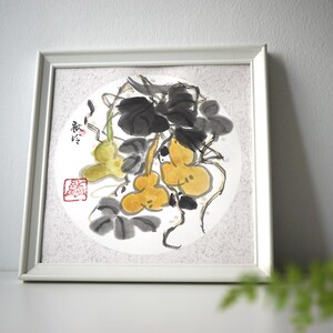 May include: A framed watercolor painting featuring a gourd and vine design. The artwork showcases yellow gourds, dark gray leaves, and stems against a white circular background. The frame is white, and the painting has Chinese characters and a red stamp.