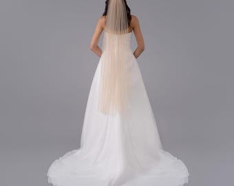 May include: A white wedding dress with a long train and a blush-colored tulle veil.