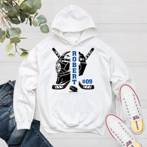 May include: White hoodie with a hockey goalie mask and sticks design. The text "ROBERT #09" is printed on the hoodie.