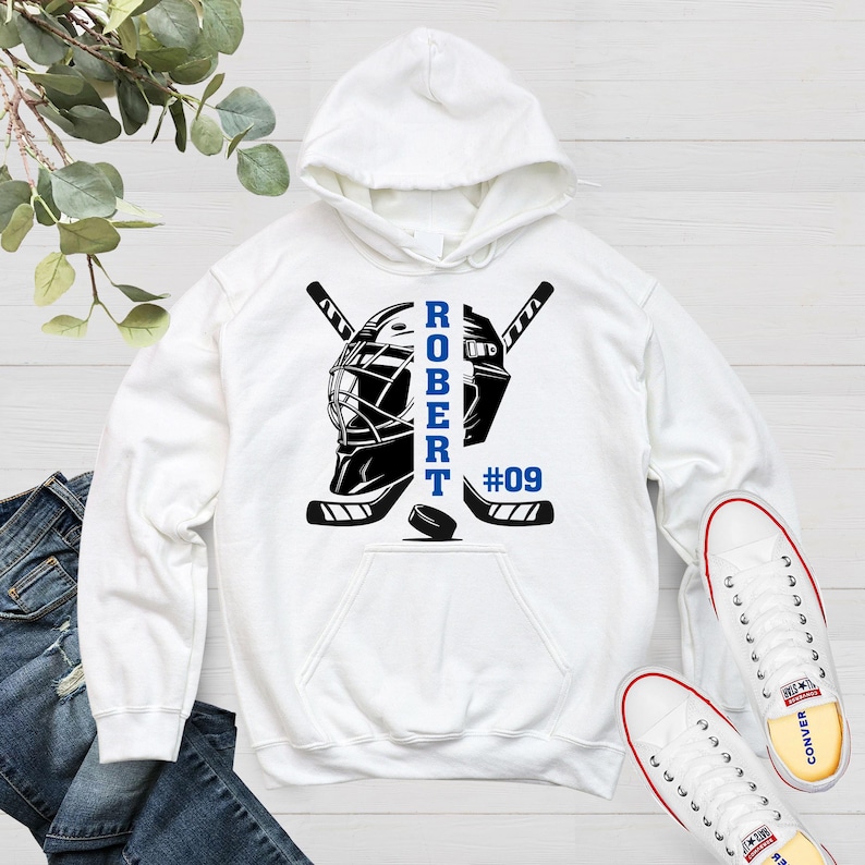May include: White hoodie with a hockey goalie mask and sticks design. The text "ROBERT #09" is printed on the hoodie.