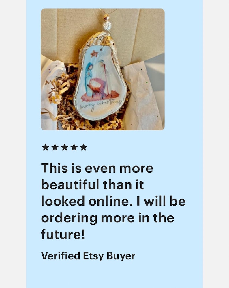 May include: A white, pear-shaped ornament with a painted image of the nativity scene and the text "Merry Christmas".