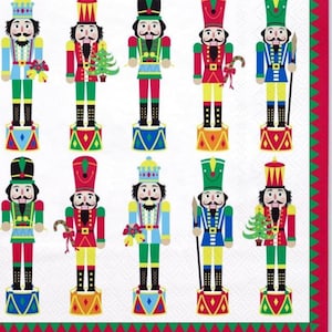 May include: A white napkin featuring a repeating pattern of colorful nutcracker soldiers. Each nutcracker is dressed in a different uniform, with details like hats, jackets, and accessories in red, green, blue, and yellow. The napkin has a red and green border.