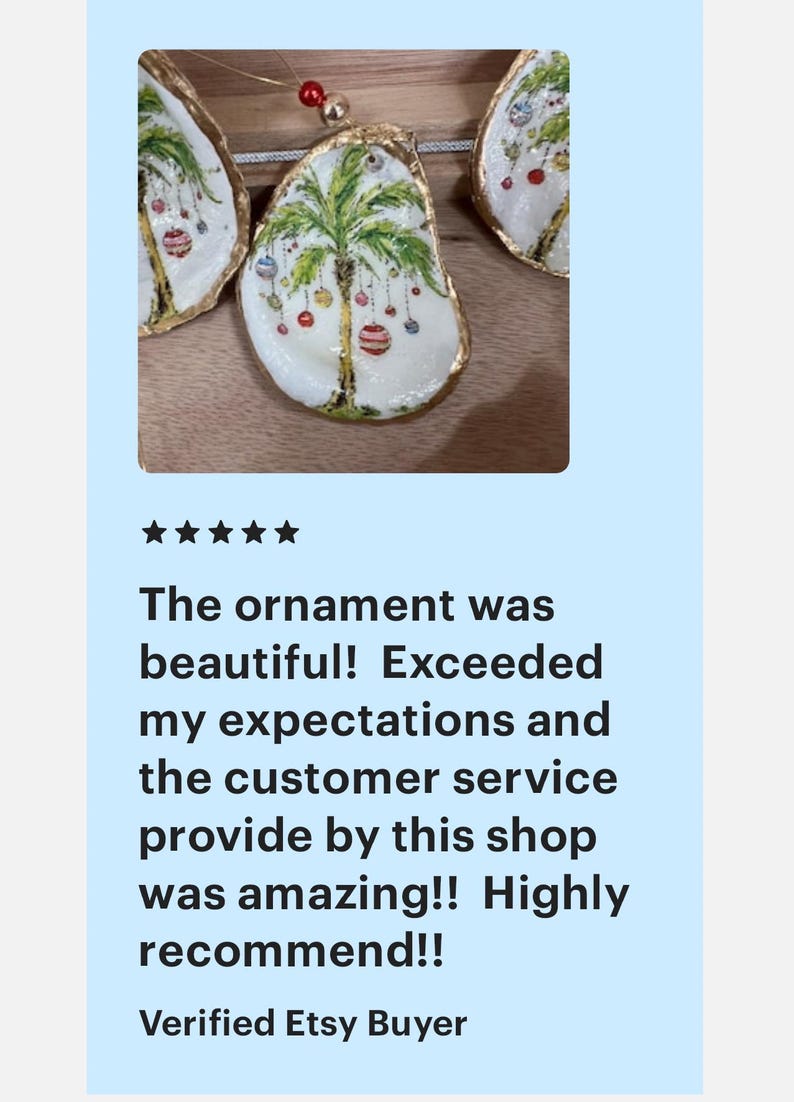 May include: Three oyster shell ornaments with gold trim, each painted with a palm tree and colorful Christmas ornaments. The ornament in the center is the largest and features a green palm tree with red, green, yellow, and white ornaments.