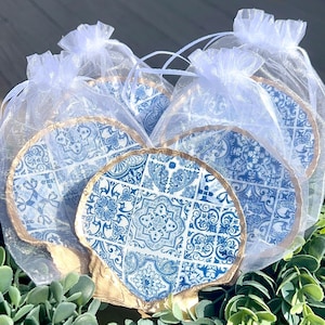 May include: Four blue and white ceramic shell-shaped trinket dishes with gold trim, packaged in white organza bags. The dishes feature a blue and white tile pattern.