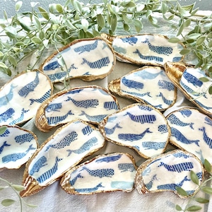 K&ouml;nnte beinhalten: Ein Set aus 12 goldger&auml;nderten Austernmuscheln mit einem blauen und wei&szlig;en Walmuster. Die Schalen eignen sich perfekt zum Servieren kleiner Snacks oder zum Aufbewahren von Schmuck.