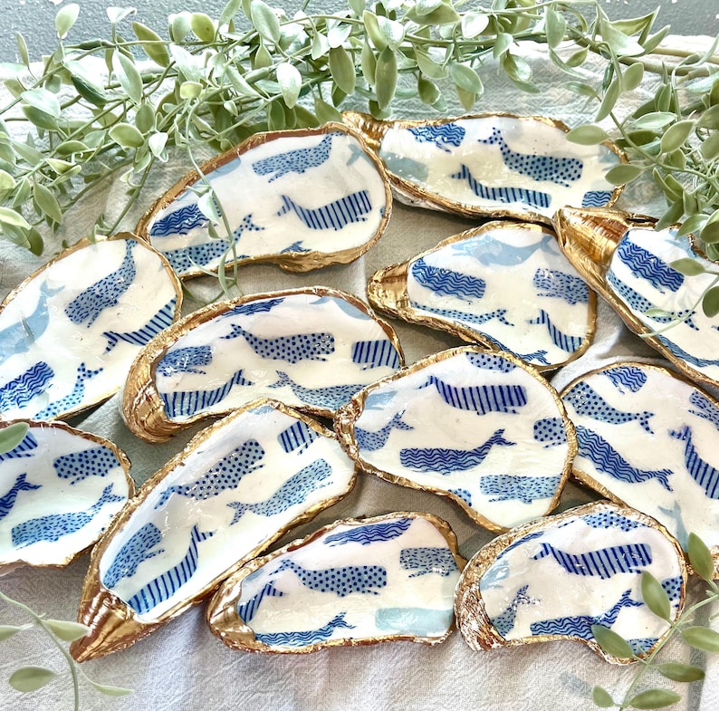 K&ouml;nnte beinhalten: Ein Set aus 12 goldger&auml;nderten Austernmuscheln mit einem blauen und wei&szlig;en Walmuster. Die Schalen eignen sich perfekt zum Servieren kleiner Snacks oder zum Aufbewahren von Schmuck.