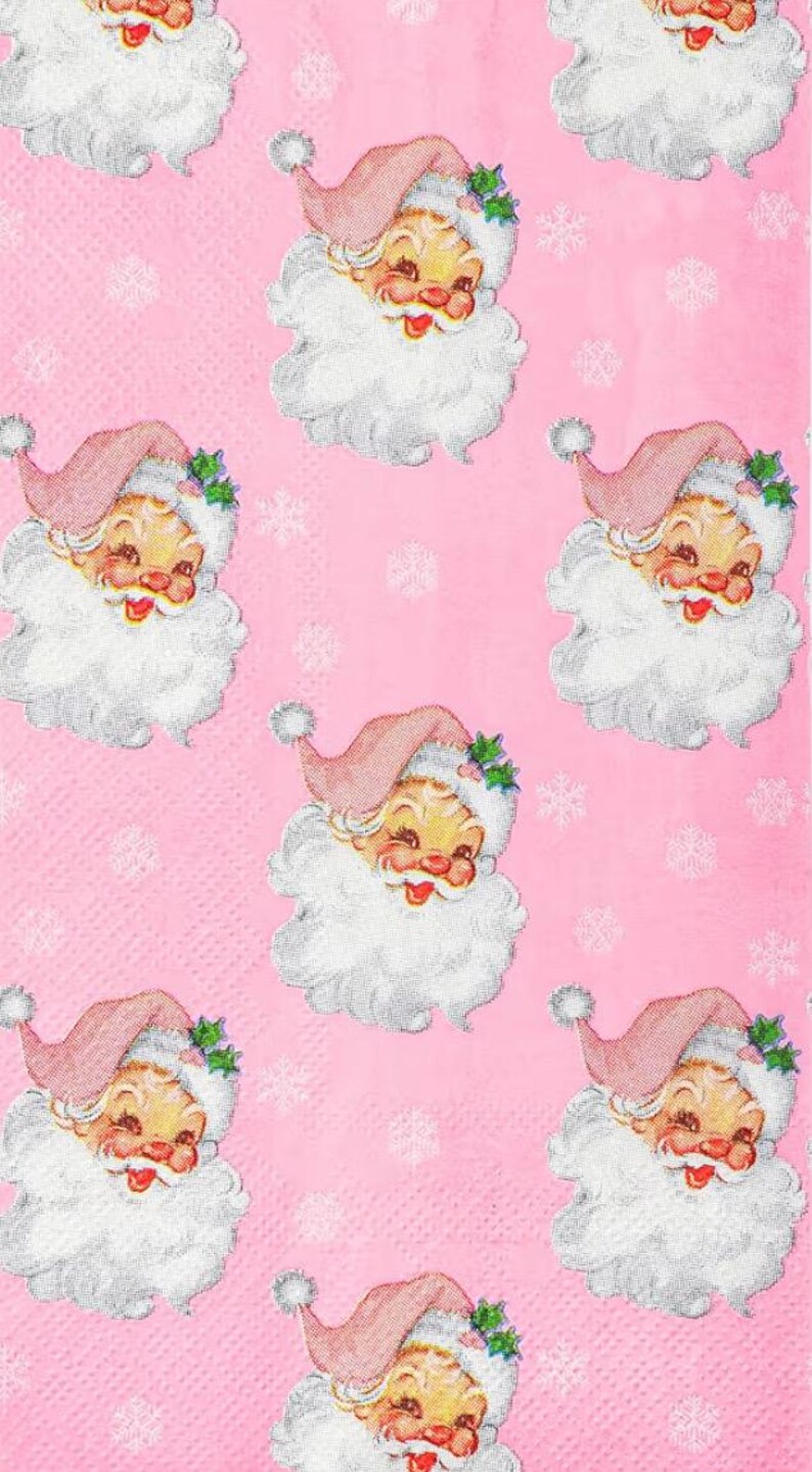 May include: Pink background with a repeating pattern of vintage Santa Claus faces. Each Santa has a pink hat, white beard, and a smiling face. Small white snowflakes are scattered across the background.
