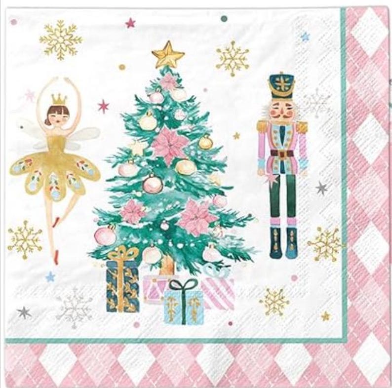 May include: A decorative Christmas-themed paper napkin featuring a watercolor illustration. The design includes a ballerina, a Christmas tree, a nutcracker, snowflakes, and wrapped gifts. The napkin has a pink and white diamond border.