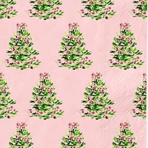 May include: Pink paper napkins with a repeating pattern of watercolor Christmas trees. Each tree is green with red ornaments and a pink bow at the top. The background is a solid light pink color.