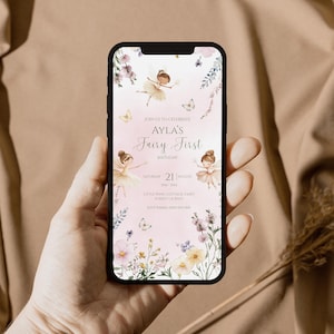 Pu&ograve; includere: Uno schermo di smartphone che mostra un invito di compleanno digitale con sfondo rosa chiaro, illustrazioni di fate ad acquerello e accenti floreali. Il testo recita: Join us to celebrate Ayla's Fairy First Birthday, Saturday 21 August, Little Wing Cottage, Fairy Forest, RSVP Emma.