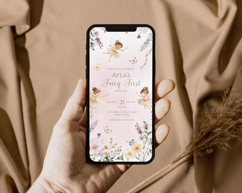 Pu&ograve; includere: Uno schermo di smartphone che mostra un invito di compleanno digitale con sfondo rosa chiaro, illustrazioni di fate ad acquerello e accenti floreali. Il testo recita: Join us to celebrate Ayla's Fairy First Birthday, Saturday 21 August, Little Wing Cottage, Fairy Forest, RSVP Emma.